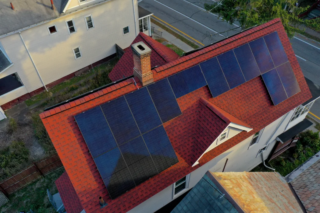 an aerial view of a house with solar panels on the red roof